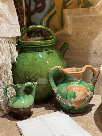 Three green glazed antique provencal pottery vessels. One small orjol, medium orjol and large gargoulette on a stone counter