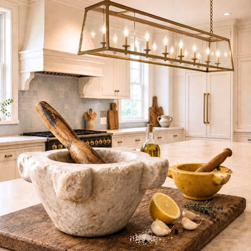 Antique French marble and glazed pottery mortars with wooden pestles styled with garlic, lemon and herbs in an elegant kitchen.