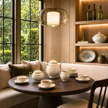 Antique French porcelain tea and coffee service with gilded cups, saucers, coffee pot, creamer and sugar bowl on an elegant dining table.