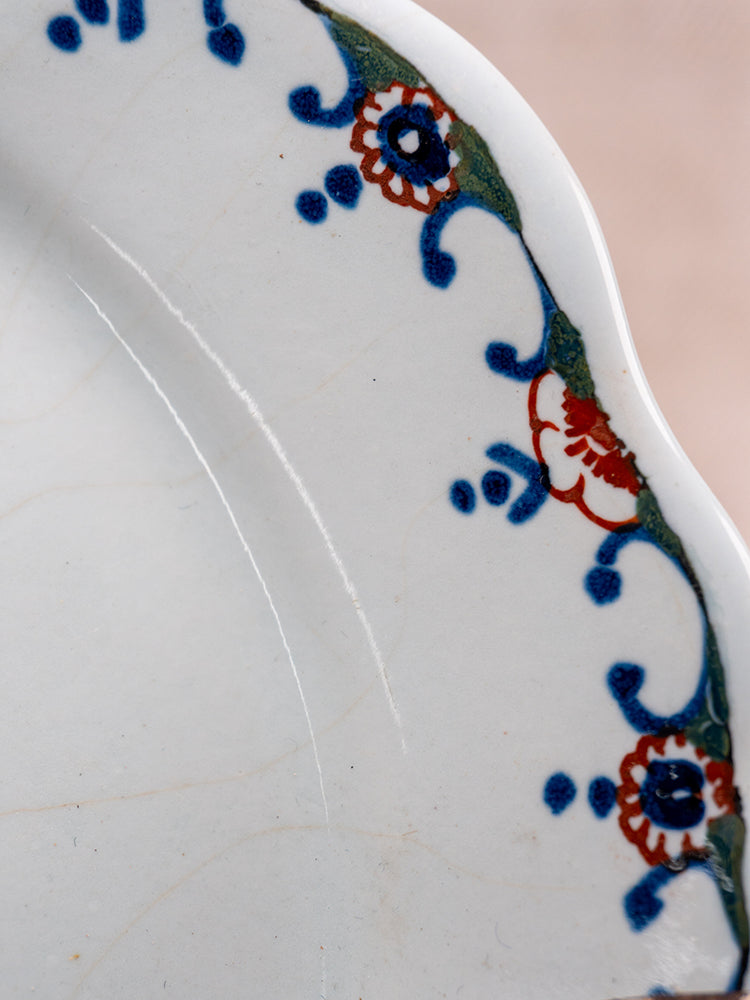Antique French Moustiers faience plate with scalloped edge, polychrome floral border, and fine enamel crackling.