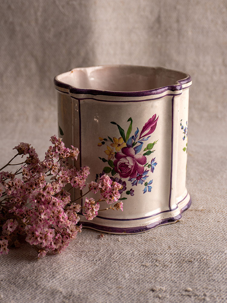 18th-century French faience cache pot, hand-painted chinoiserie with purple trim and florals on beige fabric background.