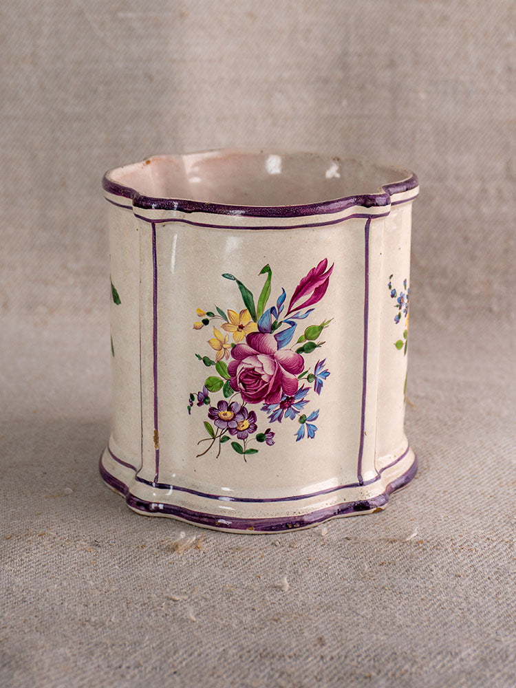 18th-century French faience cache pot, hand-painted chinoiserie with purple trim and florals on beige fabric background.