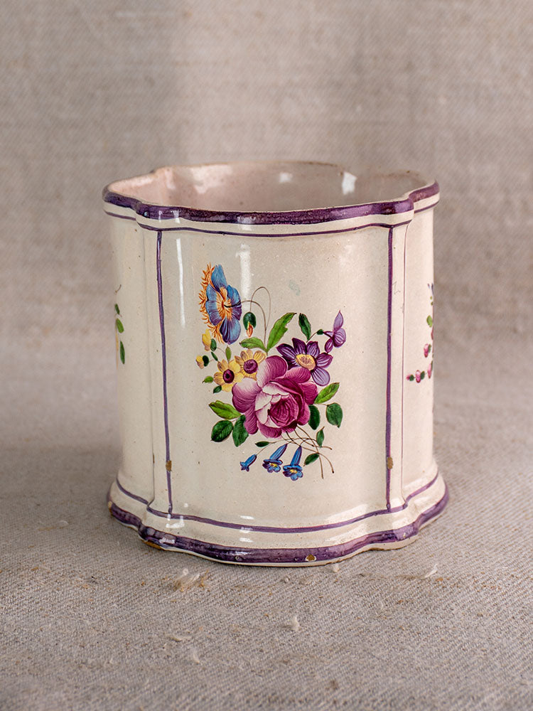 Antique 18th-century French faience cache pot with cream base, purple trim, and chinoiserie floral motifs in pink, blue, and yellow.