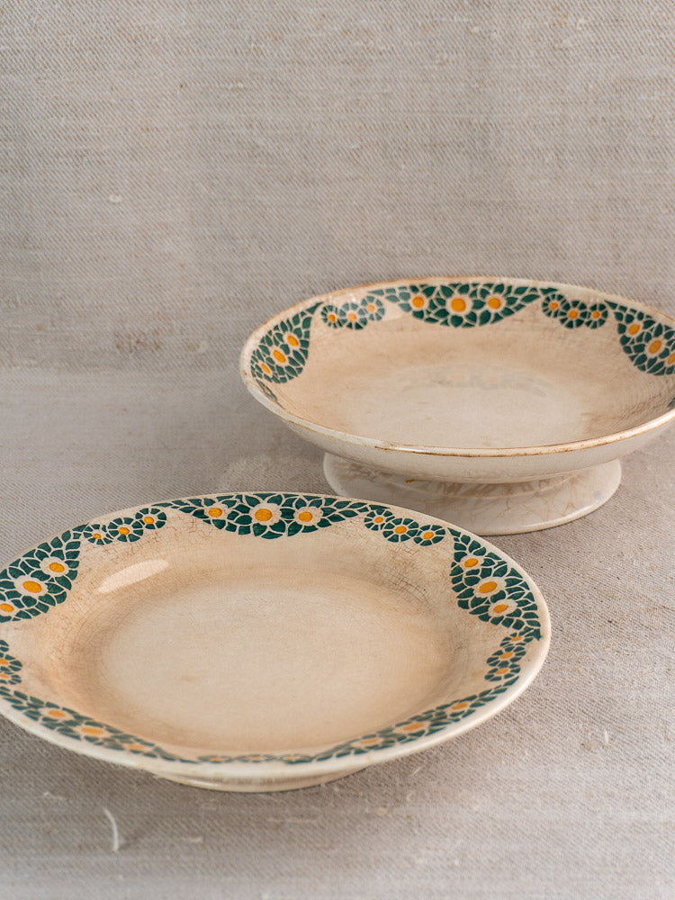Pair of antique French faience plates, Trebeurden pattern, green and yellow floral border, on beige fabric.