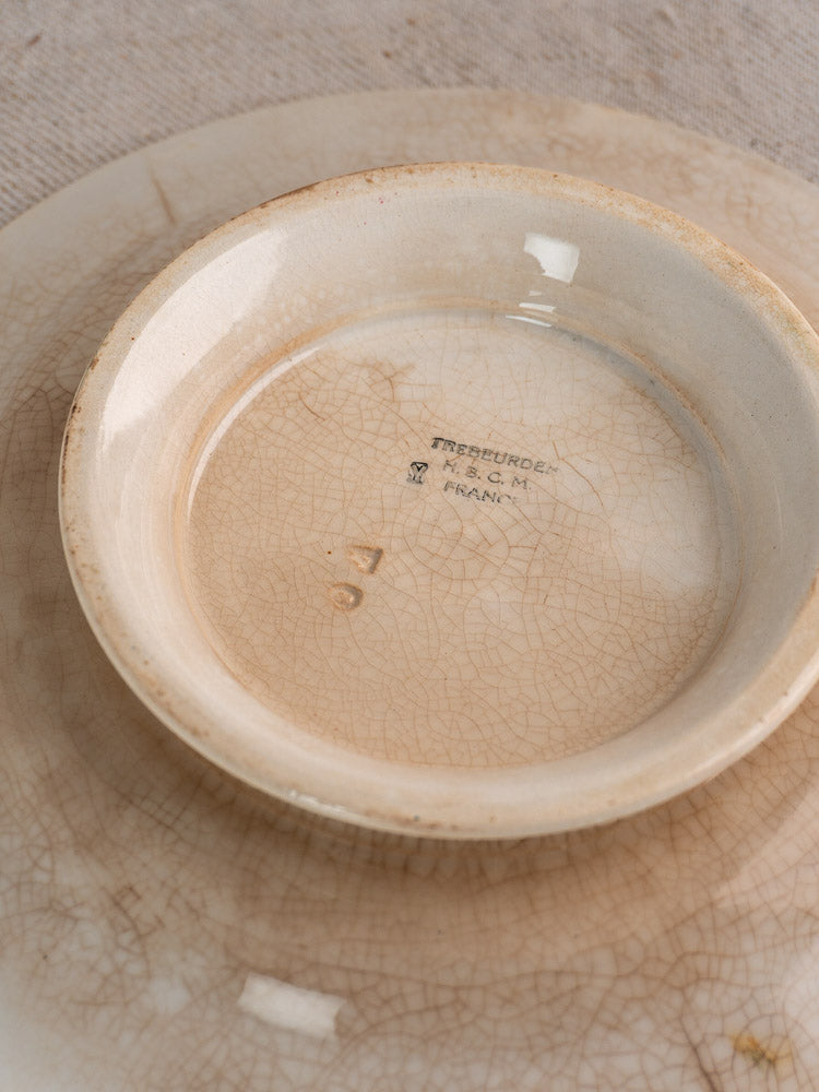 Antique French faience plate set by HBCM Creil Montereau Trebeurden, small dish atop plate on neutral fabric.