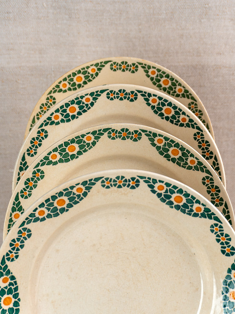 Set of four HBCM Creil Montereau French faience plates, Trebeurden pattern, floral rims, stacked on neutral fabric.