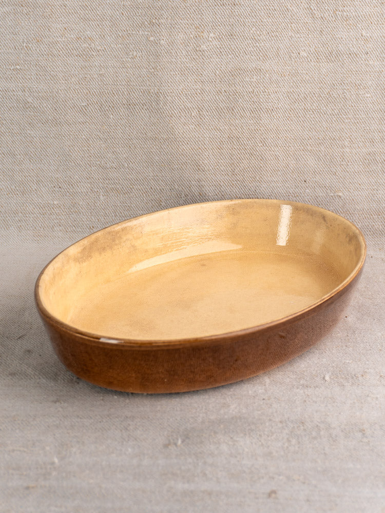 Pair of vintage French La Bourguignonne stoneware gratin dishes with brown exteriors on light gray fabric.