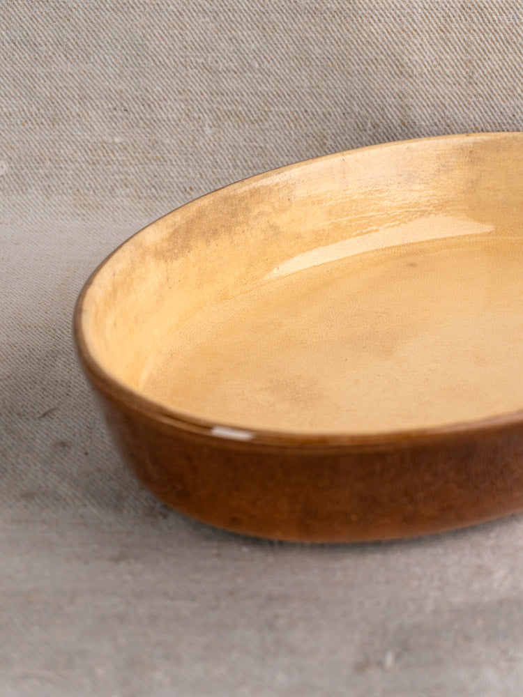 Pair of vintage French La Bourguignonne brown glazed gratin dishes on light textured fabric.