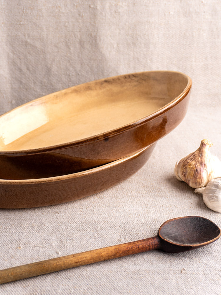 Pair of vintage French La Bourguignonne gratin dishes in brown stoneware with wooden spoon and garlic.