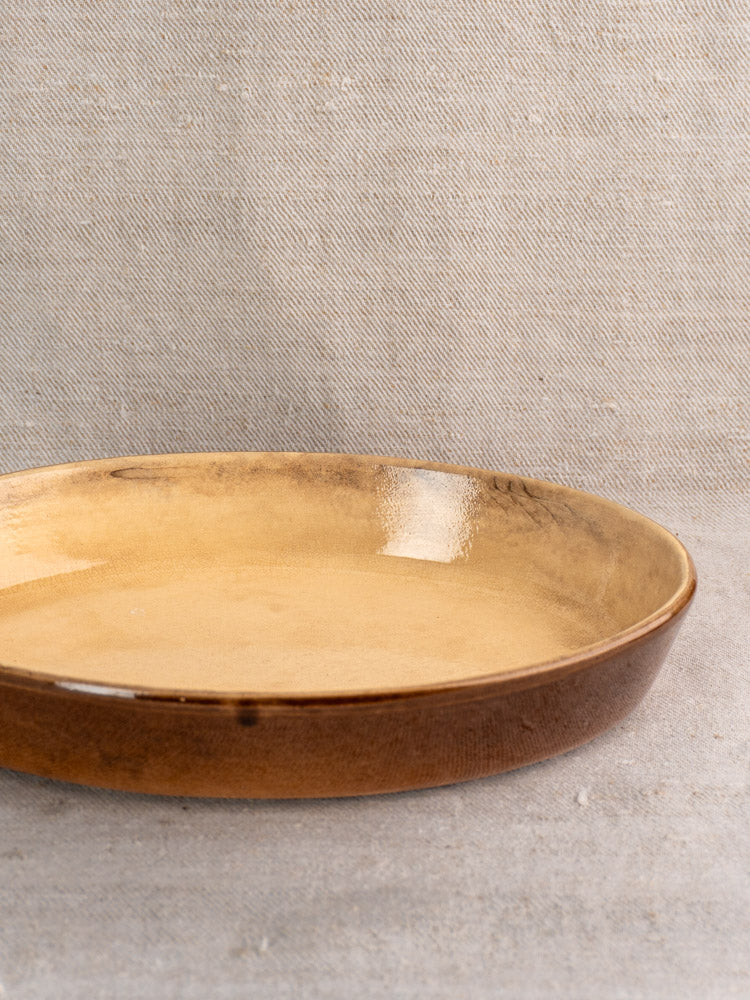 Pair of vintage French La Bourguignonne stoneware gratin dishes with glossy brown finish on beige fabric.