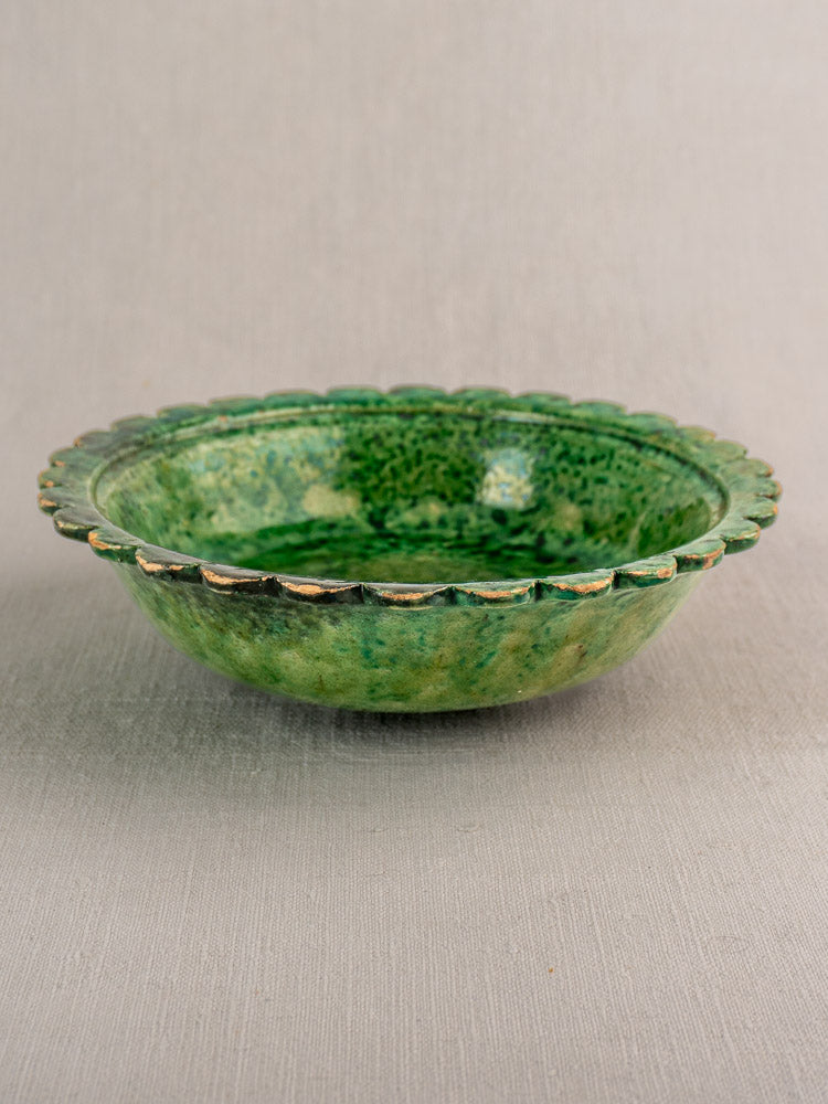 Antique French earthenware bowl with scalloped rim and Provençal green glaze, late 19th–early 20th century, on gray background.
