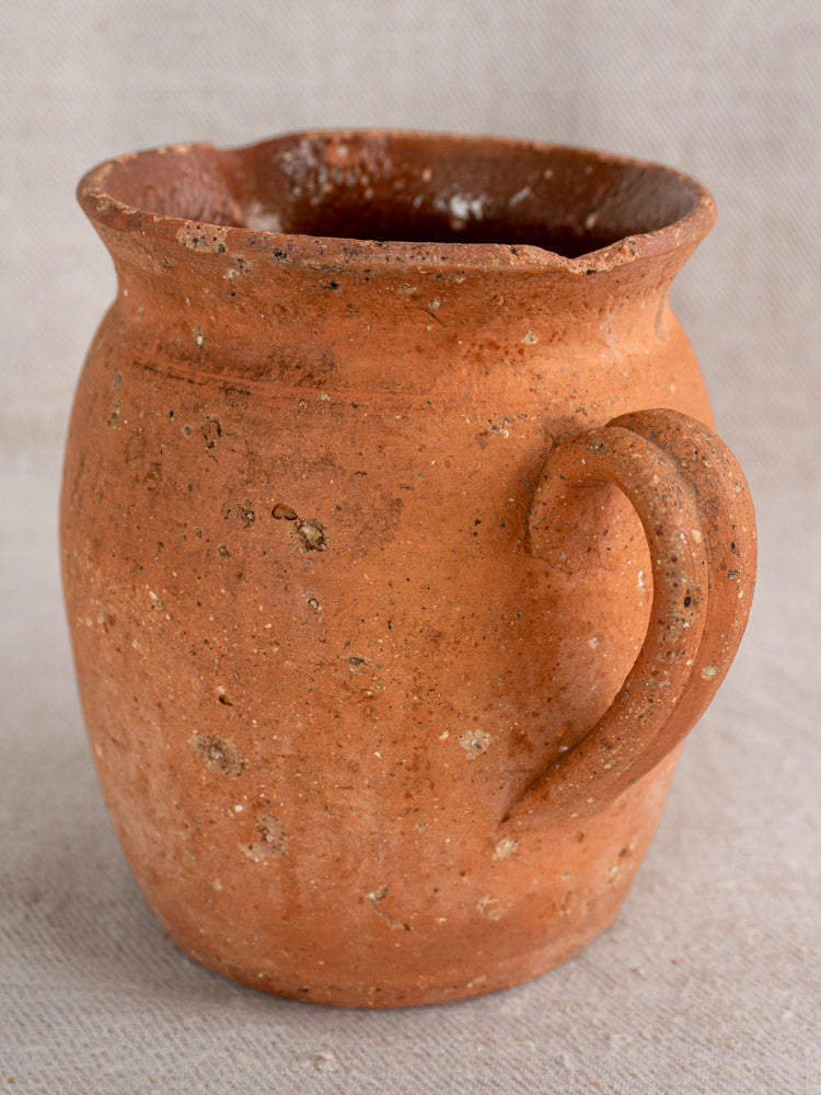 Antique French terracotta pitcher with pinched pouring lip, rustic brown glaze, and classic 19th-century pottery details.