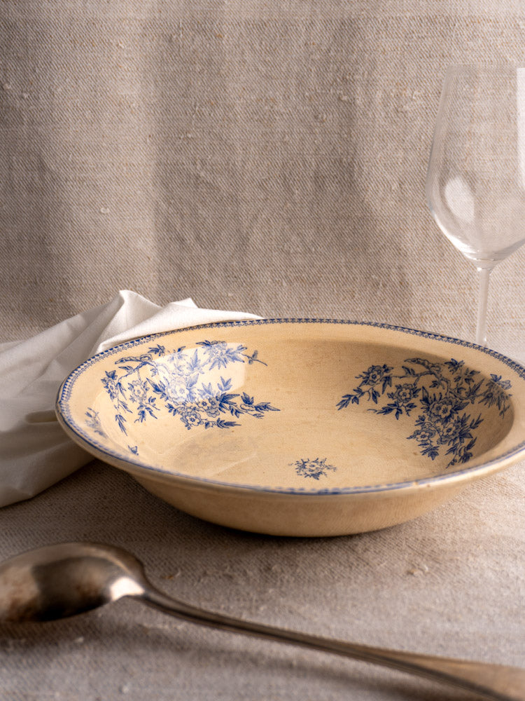 Antique French Grigny Terre de Fer salad bowl, cream glaze, blue floral motifs, on textured cloth.