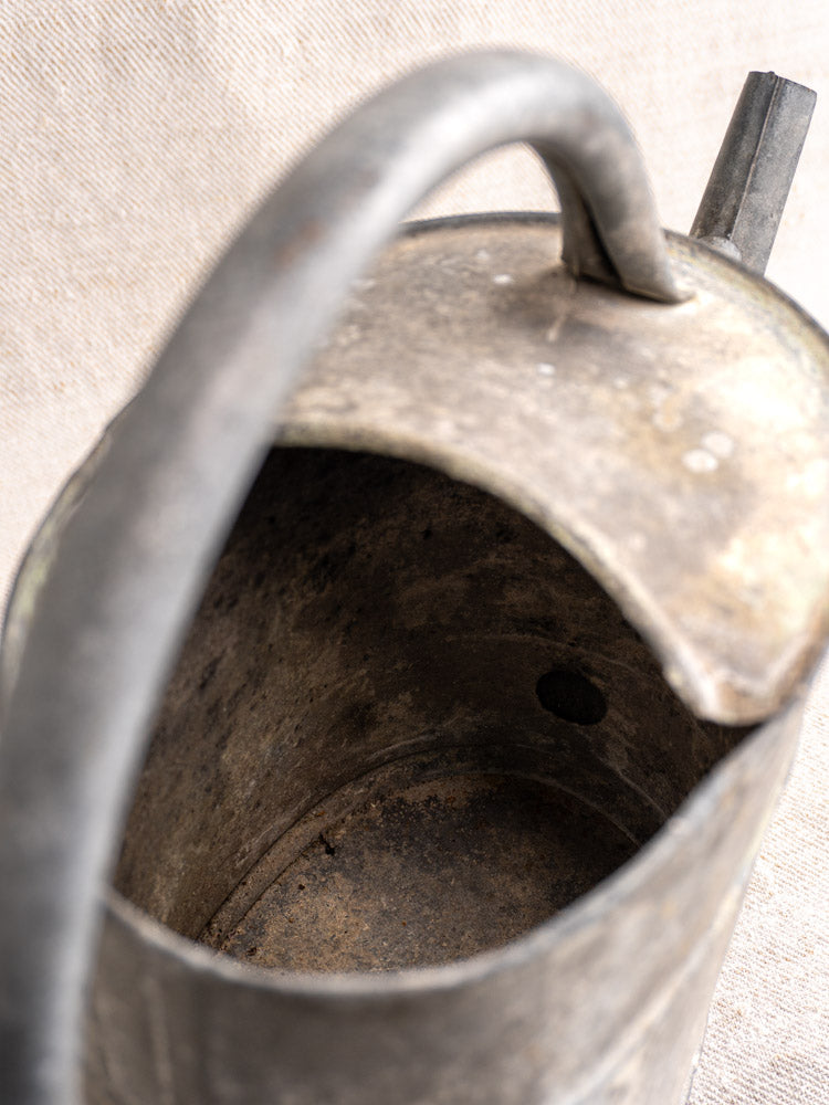 Antique French zinc watering can with curved handle and spout, late 19th–early 20th century, on a neutral background.