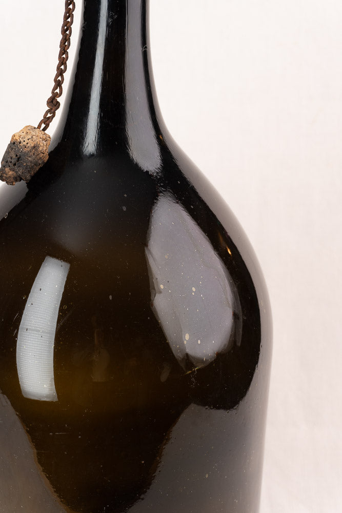 Antique French demijohn in dark olive hand-blown glass with original chain and cork, shown on a plain white background.
