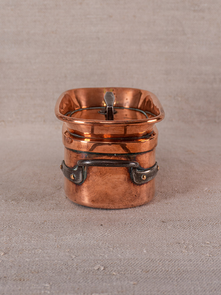 19th-century French copper apprentice set with daubiere and saucepans on textured beige fabric.