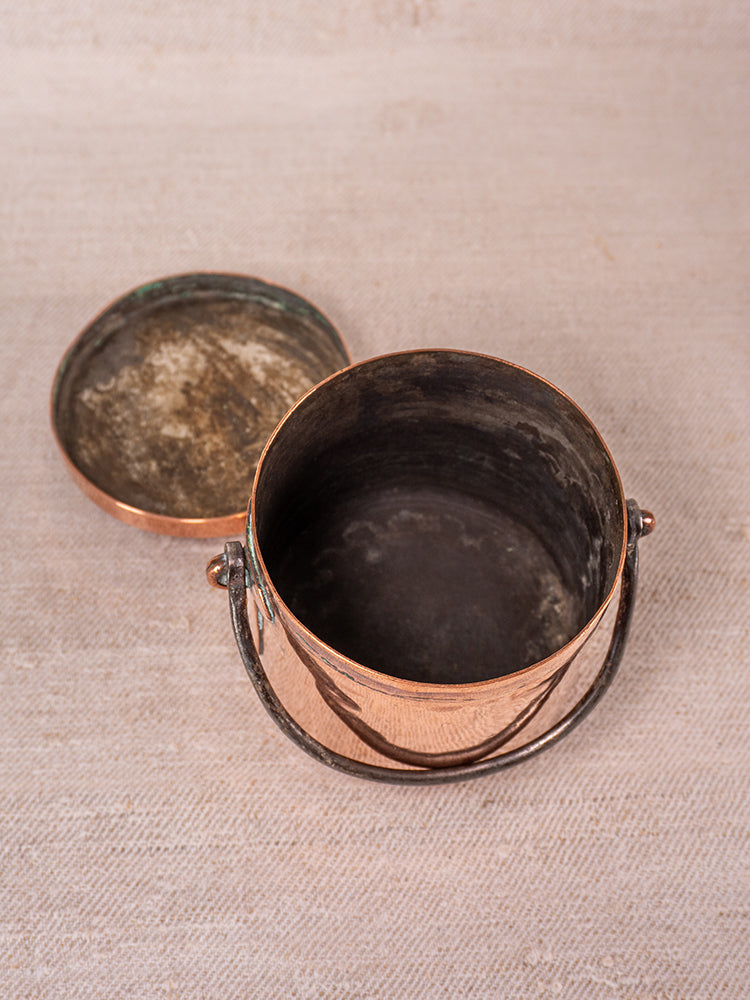 19th-century French copper apprentice daubiere and saucepans with patina displayed on a light, textured surface.