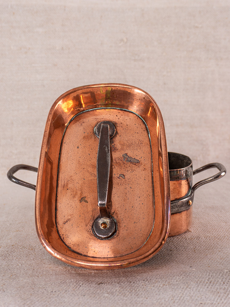 Antique French copper apprentice set with 19th-century daubiere and saucepans, shown on neutral fabric background.