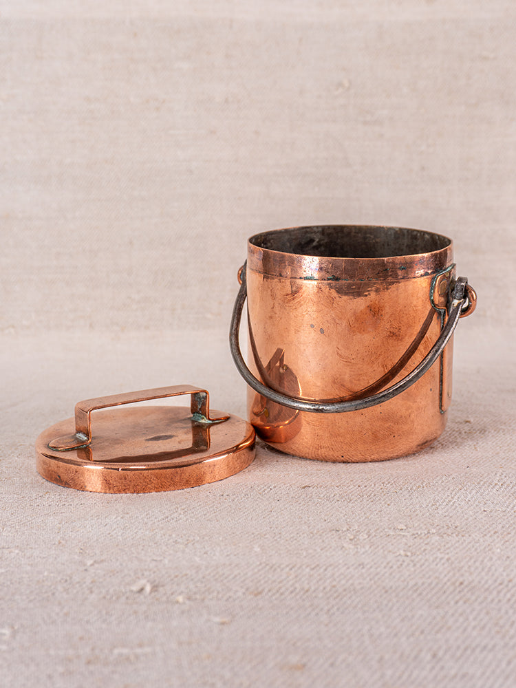 19th-century French copper saucepan with handle, lid off, subtly tarnished on beige fabric background.