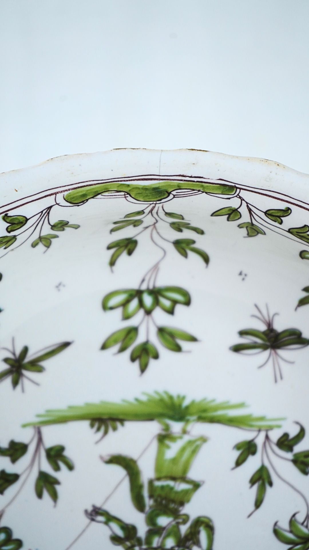 French faience chinoiserie bowl with hand-painted green and brown plant and insect motifs on earthenware.