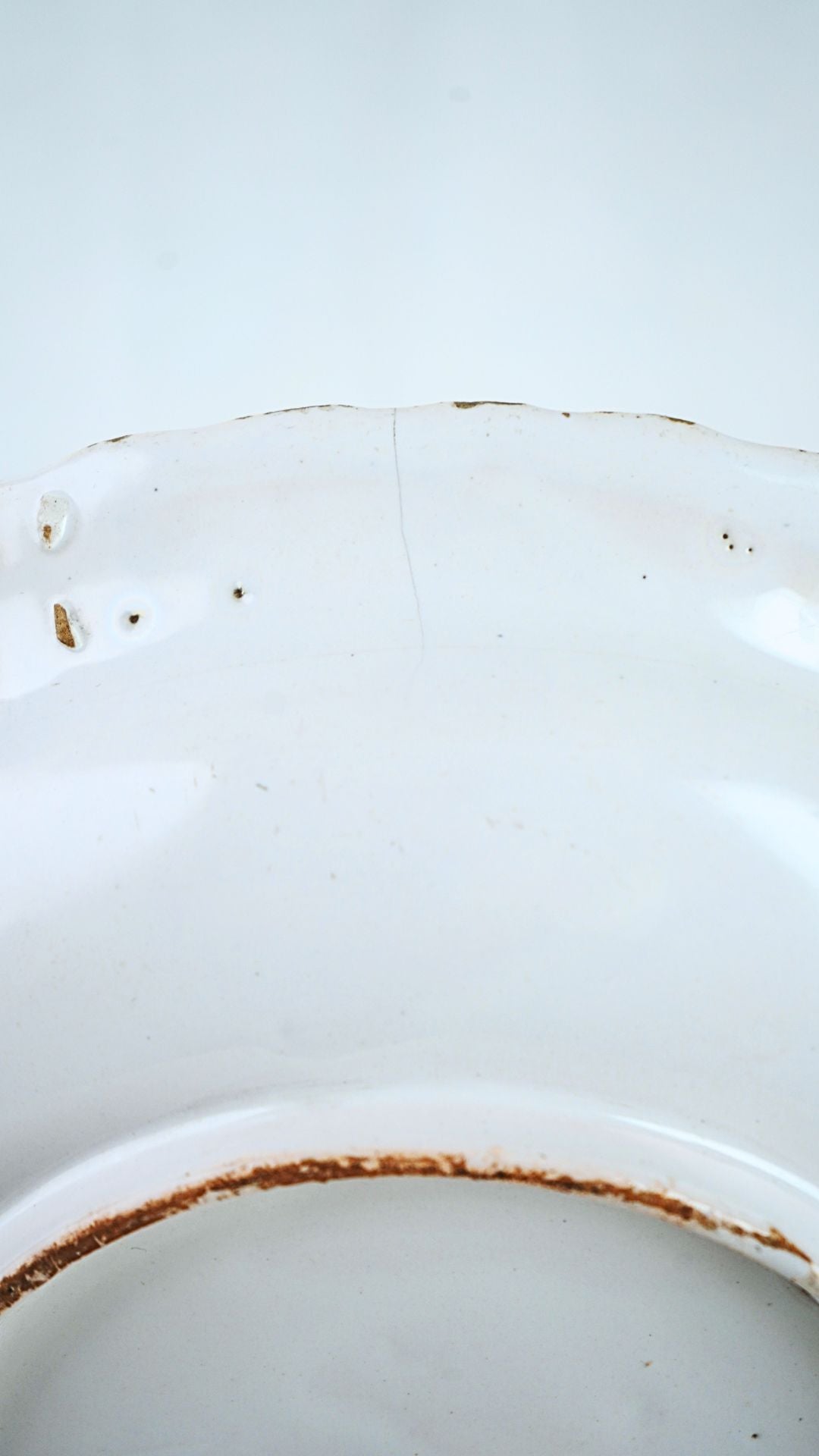 French Faïence Chinoiserie bowl in white glaze, featuring a hairline crack and rust-colored base rim.