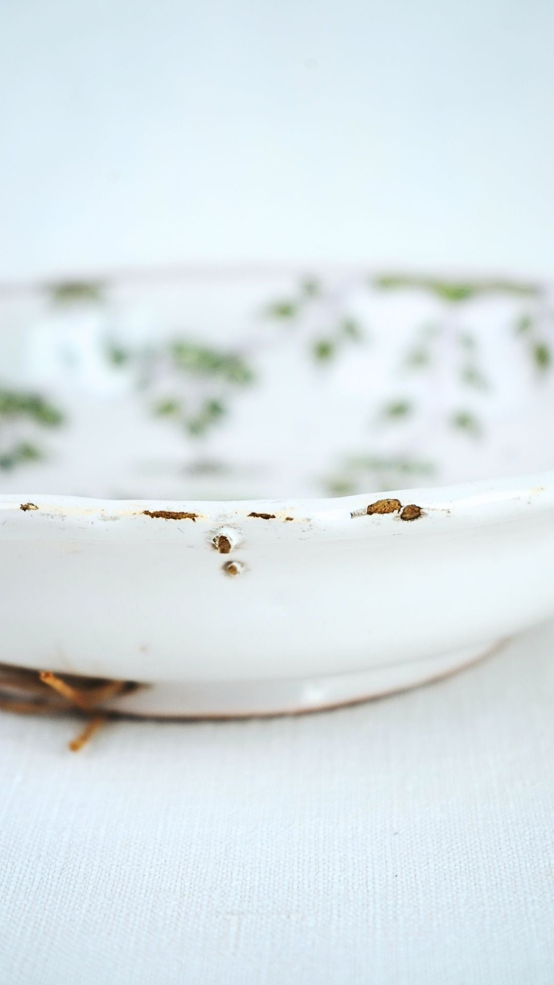 18th-century French faience chinoiserie bowl with green floral pattern and chipped glaze along rim.