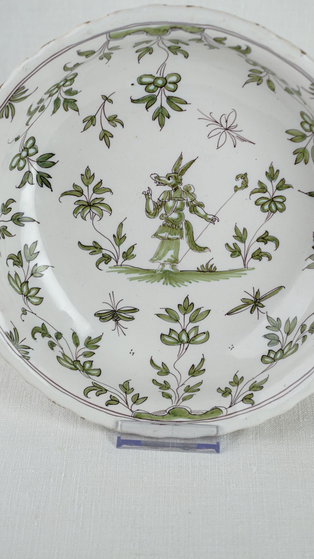 18th-century French faience chinoiserie bowl featuring a central anthropomorphic animal figure and green floral motifs.
