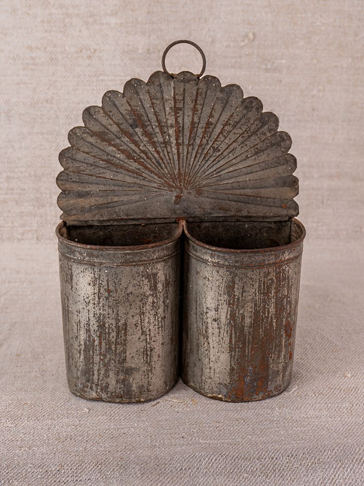Provençal wall-mounted utensil holder in aged steel with dual compartments, vintage patina, on neutral fabric background.