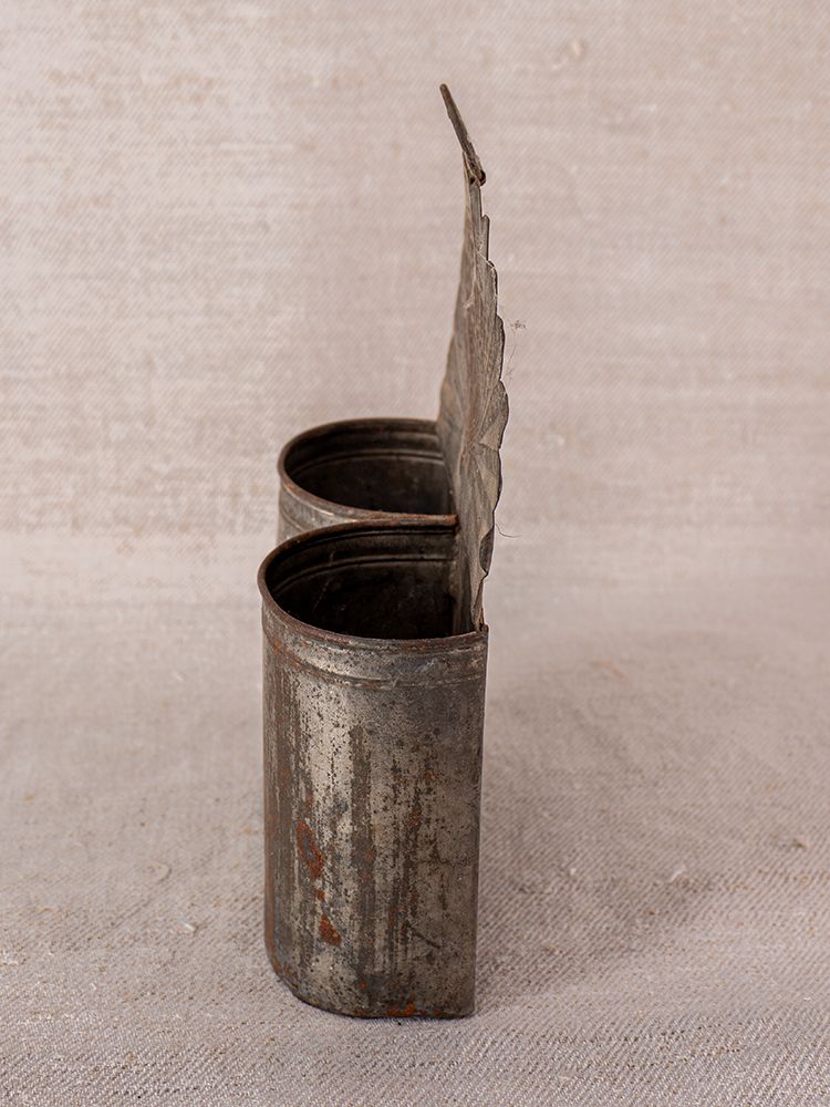 Provençal wall-mounted aged steel utensil holder with scalloped lid and dual compartments on a textured beige surface.