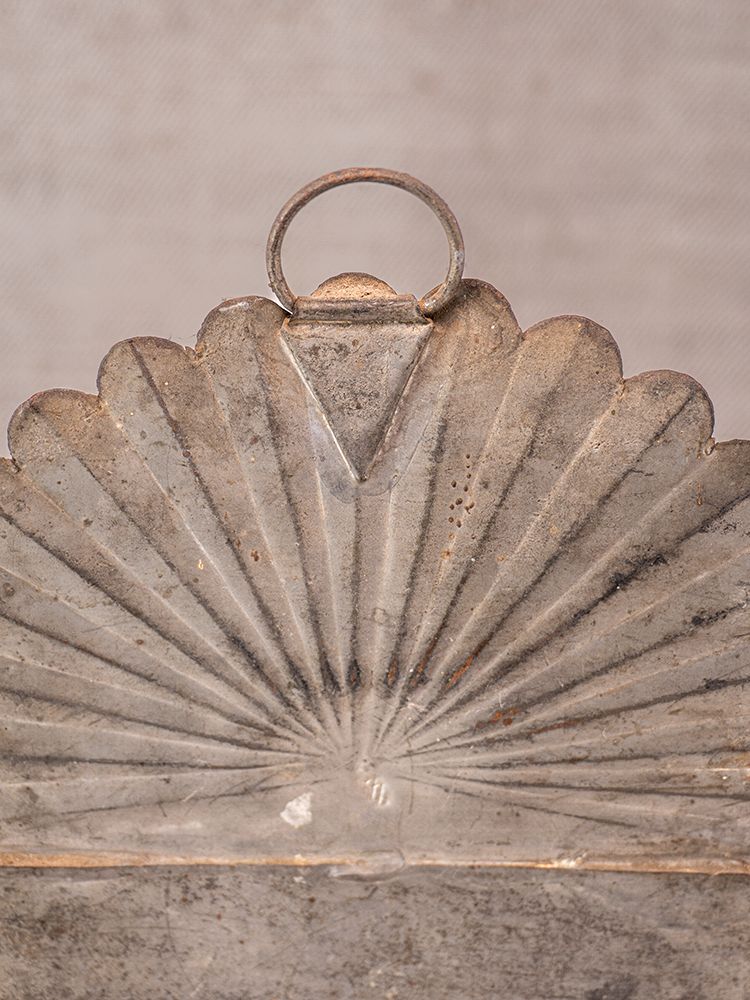 Provençal wall-mounted utensil holder in aged steel with scalloped fan design and circular handle, neutral textured backdrop.