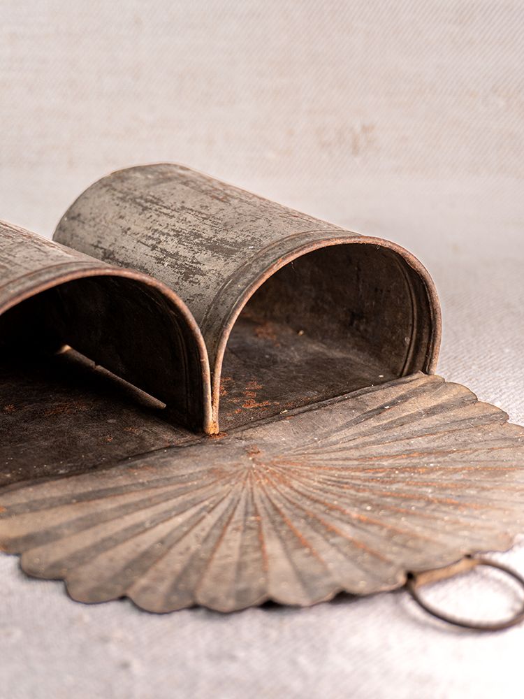 Antique Provençal wall-mounted aged steel utensil holder with scalloped base and rustic patina on neutral background.