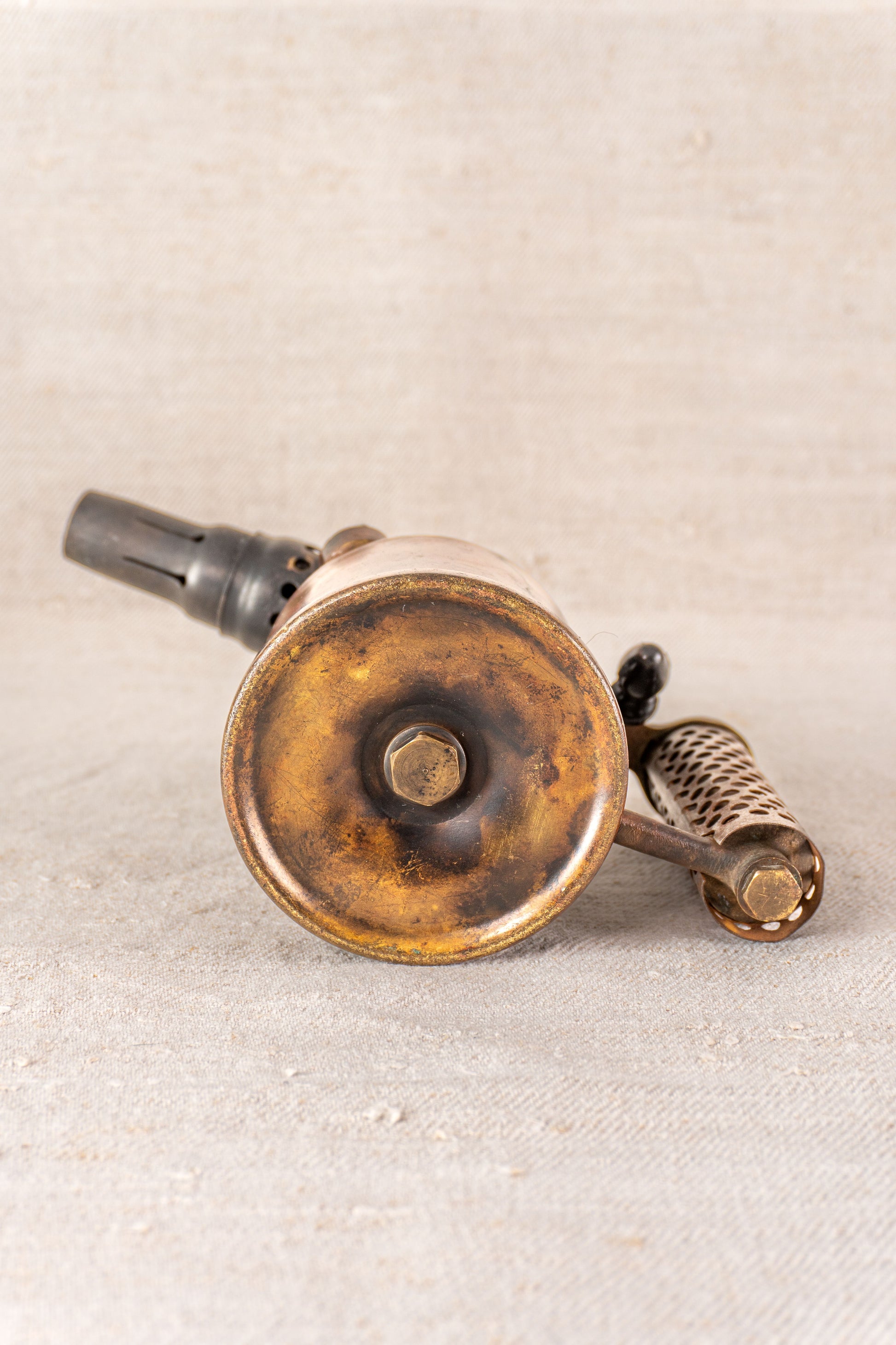 Vintage French Vesta F.J. Paris blowtorch from circa 1920, displayed on a light textured surface showing base and handle.
