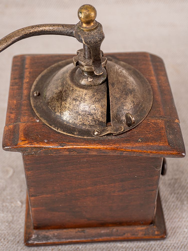 Antique French Peugeot Frères coffee grinder with wood body, metal handle, and dome top on a textured surface.