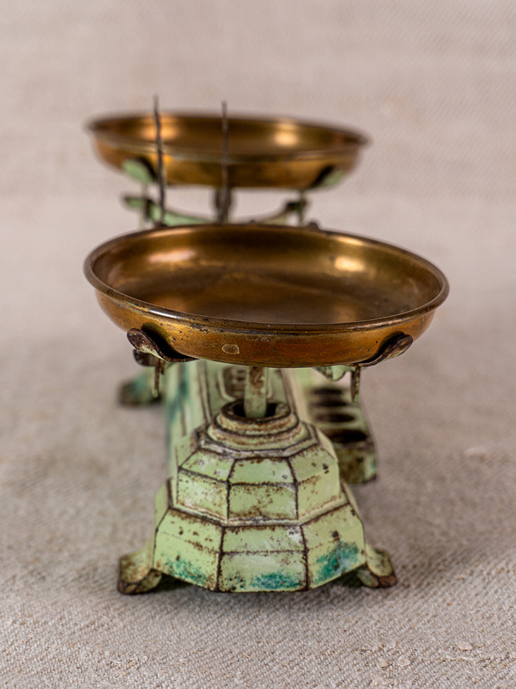 Vintage French JEP toy balance scale in green cast iron with brass pans on beige surface.