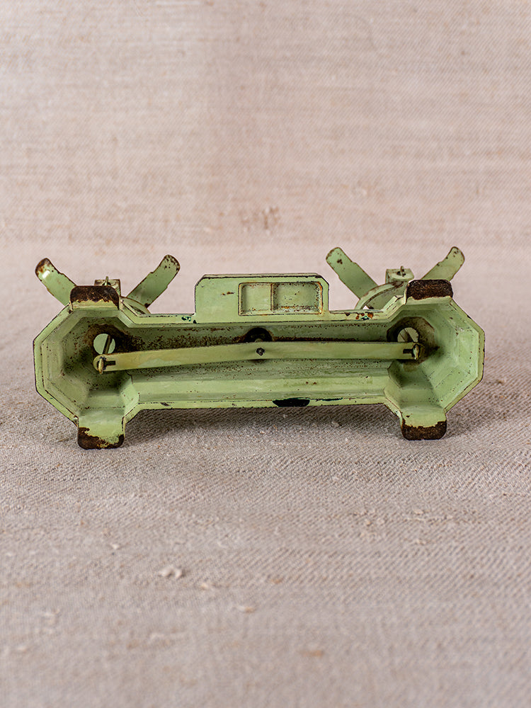 Vintage French JEP toy balance scale in green cast iron with brass accents, shown upside down on beige.