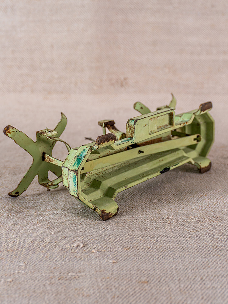 Vintage French JEP toy balance scale in green cast iron with brass accents, on textured beige surface.