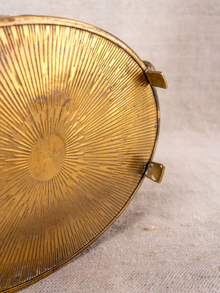 Vintage Swiss brass jardinière, mid-century oval tray with embossed fruit motif, on textured beige fabric.