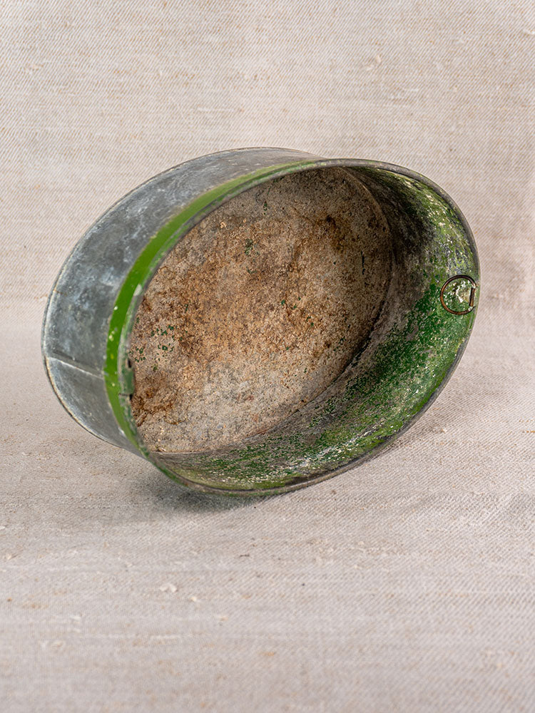 Vintage Swiss brass jardinière with embossed fruit motif in mid-century style on textured beige fabric background.