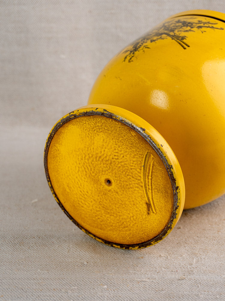 Vintage French tôle peinte champagne cooler in yellow Directoire style, showing worn textured base on neutral fabric.
