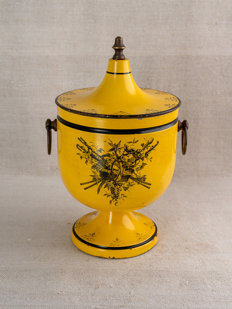 Vintage French yellow tôle peinte champagne cooler in Directoire style with floral black accents, on neutral fabric.