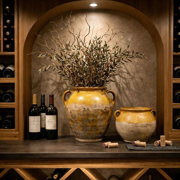pottery and ceramics collection featuring antique French yellow glazed pots styled in a wine cellar with olive branches and warm ambient light