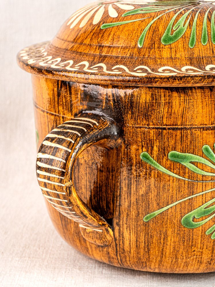 Antique French terracotta cookware set with green and white slip decoration, light neutral background.