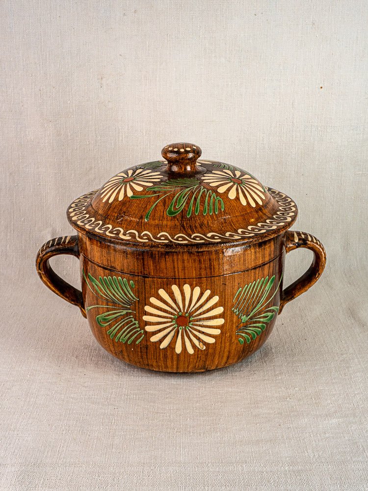 Antique French terracotta cookware set from Alsace with white and green floral decoration, on fabric.
