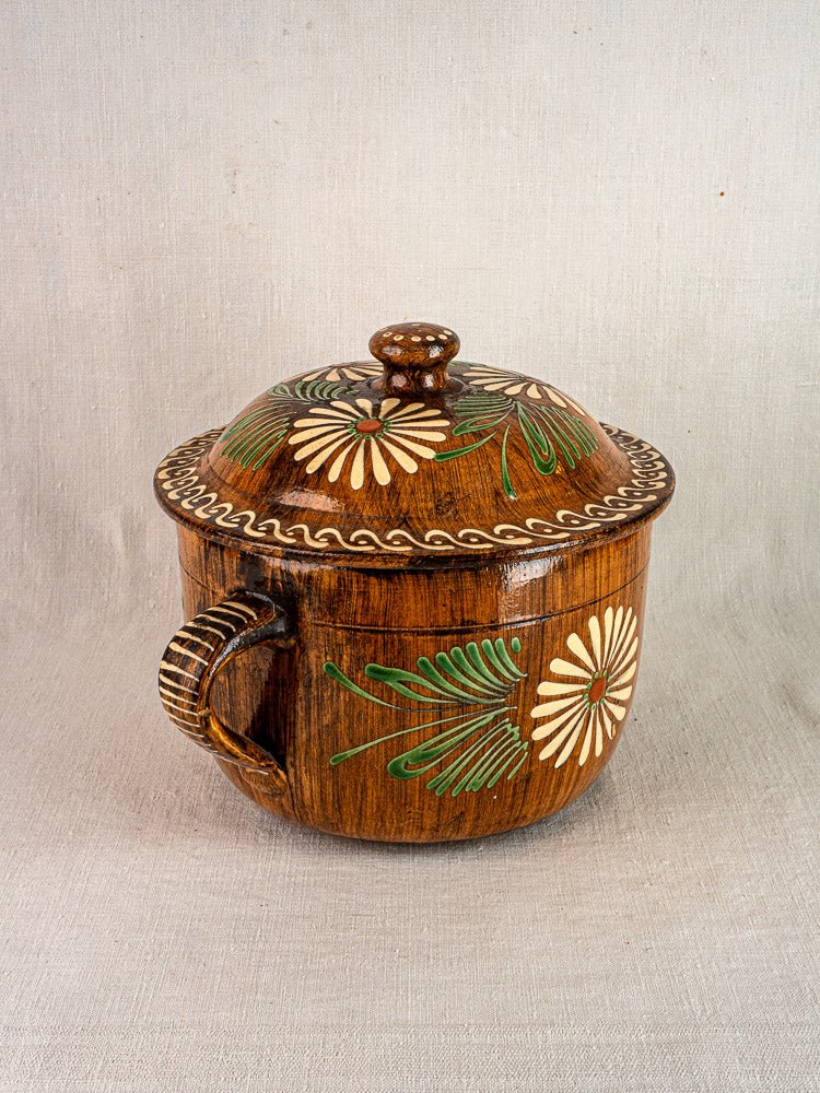 Antique French Alsace glazed terracotta cookware with white and green slip floral patterns on light textured surface.