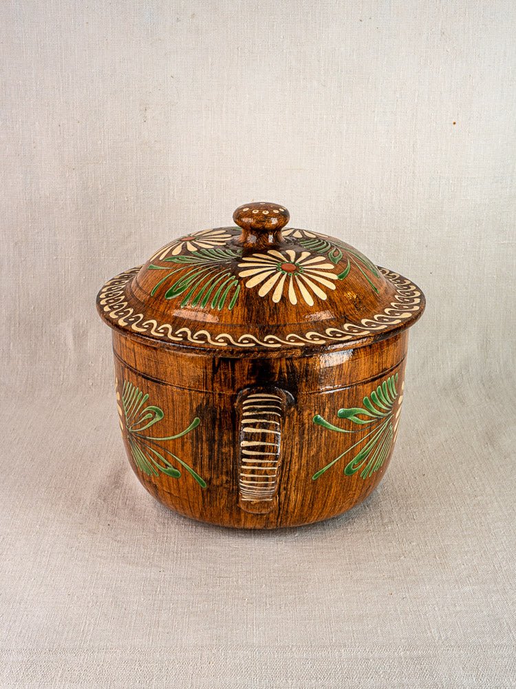 Antique French terracotta cookware set from Alsace with green and yellow floral slip decoration on light fabric.