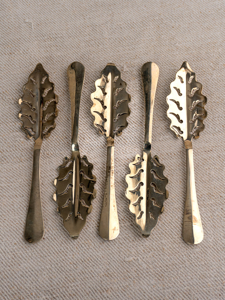 Set of 10 antique French absinthe spoons by Cailar Bayard with ornate, intricate leaf-pattern detailing.