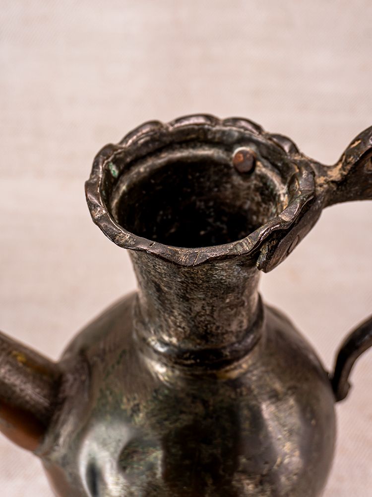 Antique Anatolian tinned copper ibrik with scalloped rim, side handle, and patina on a neutral background.