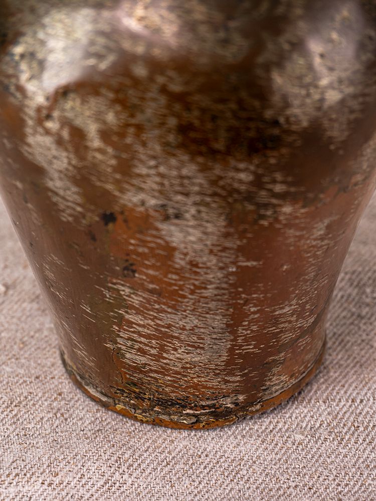 Antique Anatolian tinned copper ibrik with tarnished brownish-gold patina, set on textured beige fabric.