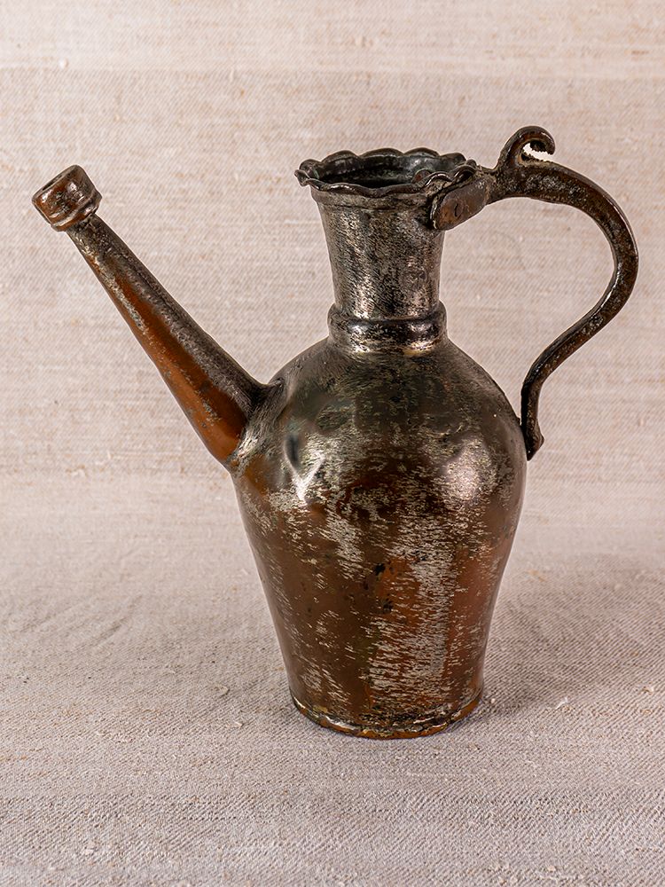 19th century Anatolian tinned copper ibrik watering can with long spout and curved handle on textured fabric.