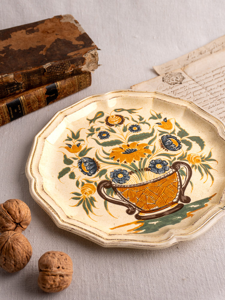 French Salins Clérissy faience plate, Moustiers style, with floral basket, staged with walnuts and antique books.